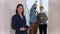 A smiling real estate agent standing in draft apartment - young married couple looking around on the background