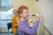 Smiling red-haired boy writing symbols on the whiteboard