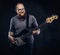 Smiling redhead bearded male musician wearing glasses dressed in a gray t-shirt playing on electric guitar. on