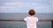 Smiling redhead boy enjoys summer evening on wooden pier by the ocean