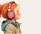 Smiling redhead child girl listening to music in pink headphones.