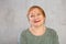 Smiling redhead senior woman in knitted jumper in studio