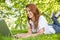 Smiling redhead using laptop in the park