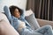 Smiling relaxed african woman lounge on comfortable sofa, portrait.