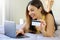 Smiling relaxed young woman lying on bed insert credit card number on notebook  doing safely shopping online at home