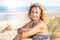 Smiling retired senior blonde woman in edge dune beach in summer