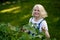 Smiling retired woman pruning black currant leaves on her garden yard