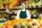 Smiling salesgirl in apron standing in fruit and vegetable store