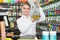 Smiling salesgirl offering perfume on tap in cosmetic boutique