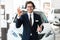 Smiling Salesman Gesturing Okay Standing In Luxury Auto Store