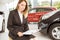 Smiling saleswoman sitting near cars