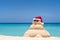 Smiling sandy snowman with red santa hat on the caribbean beach. Holiday concept for New Year and Christmas Cards