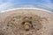 Smiling sandy snowman in red santa hat on the sea