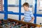 Smiling school boy playing table soccer. Happy excited child having fun with family game with siblings or friends