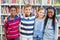 Smiling school kids standing with arm around in library