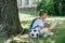 Smiling schoolboy reading book while sitting on lawn near soccer ball