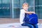 Smiling schoolboy sitting with his backpack outdoor. Education, back to school, travel concept