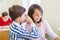 Smiling schoolboy whispering to classmate ear