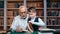 Smiling schooler boy bringing ancient retro book learning history science grandfather at library