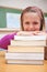 A smiling schoolgirl posing with a stack of books