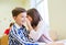 Smiling schoolgirl whispering to classmate ear