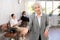 Smiling secretary senior woman stands at entrance to office reception and expects visitors