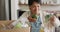 Smiling senior biracial woman grabbing vegetables from box in kitchen alone