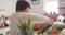 Smiling senior biracial woman grabbing vegetables in kitchen alone