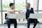 Smiling Senior Caucasian businessman shaking hand with young Asain businessman and working with laptop.