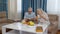 Smiling senior couple grandfather, grandmother resting on sofa drinking coffee, reading book at home