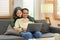 Smiling senior couple hugging and using laptop on comfortable couch. Elderly and technology concept