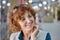 Smiling senior European woman with curly brown hair in a shopping mall interior, face close-up