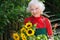 Smiling senior lady gardening in her yard.