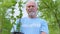 Smiling senior male volunteer holding tree sapling, nature conservation, ecology