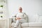 Smiling senior man in glasses sitting on sofa