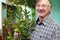 Smiling senior man looking after houseplant lemon