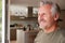 Smiling Senior Man Standing And Looking Out Of Kitchen Door