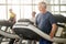 Smiling senior man on treadmill at gym.