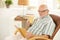 Smiling senior relaxing at home with book and tea