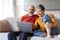 Smiling Senior Spouses Resting With Laptop In Living Room Interior