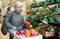 Smiling senior woman choosing christmas decorations in shop