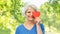 Smiling senior woman covering eye with red heart