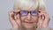 Smiling senior woman fitting eyeglasses, elderly customer in optical store