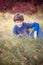 Smiling seven year old boy portrait sitting in field in Autumn