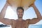 Smiling shirtless man carrying surfboard at beach