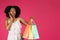 Smiling shocked millennial black lady with open mouth show many packages with purchases