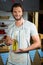 Smiling shop assistant holding olive oil bottle