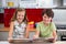 Smiling siblings looking at photo album in kitchen