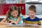 Smiling siblings looking at photo album in kitchen