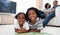 Smiling siblings reading lying on the floor